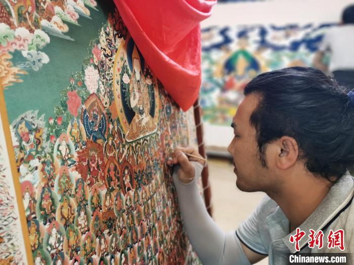 圖為更登才讓的徒弟繪畫唐卡?！?zhí)砀?攝
